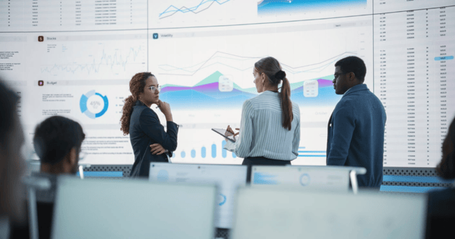 A group of business people standing in front of a screen