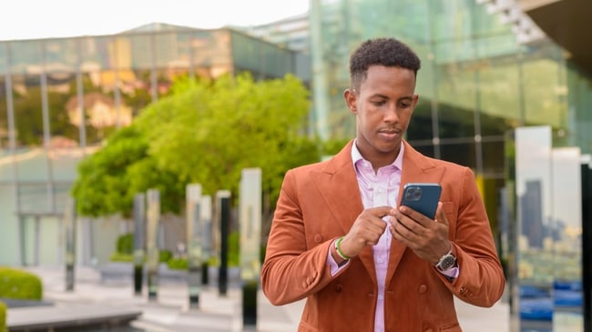 A businessman browsing on his phone outside