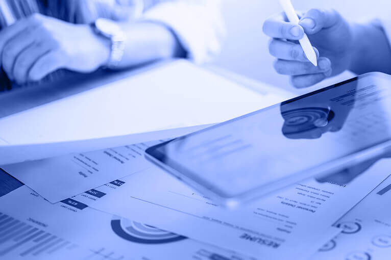 Blue Image of People Looking at Paper Documents and a Tablet