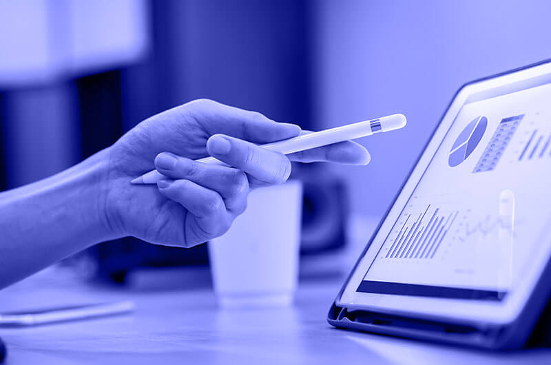 Blue Image of a Person Pointing at Graphs on a Tablet using a Pen