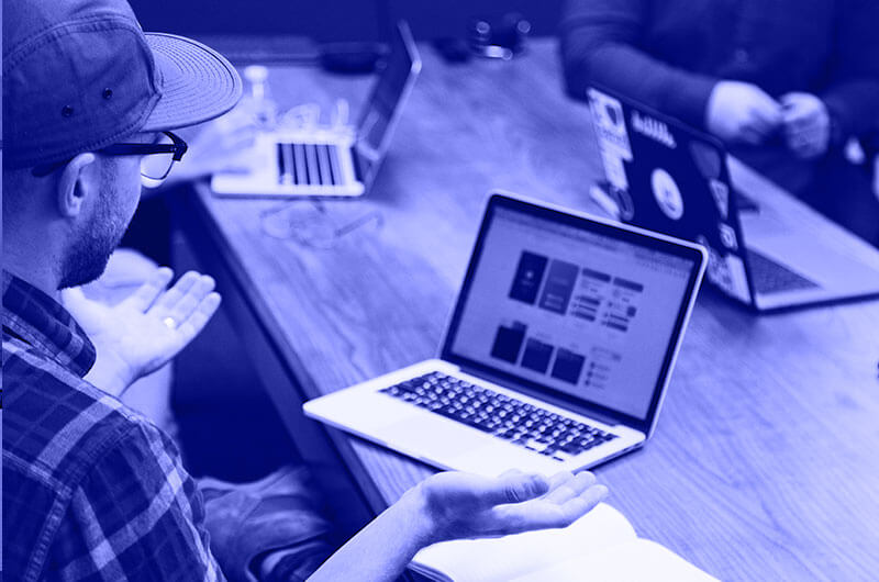 Blue Image of People Working on Laptops at a Table
