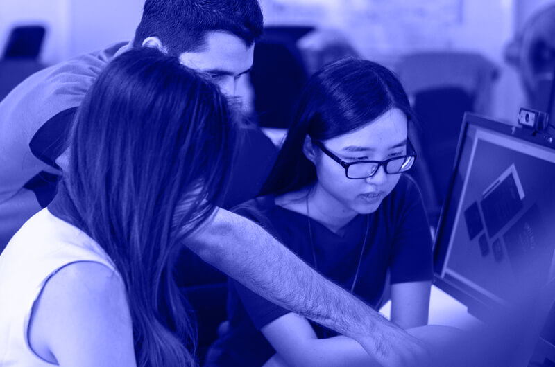 Blue Image of Three People Looking at a Computer Screen