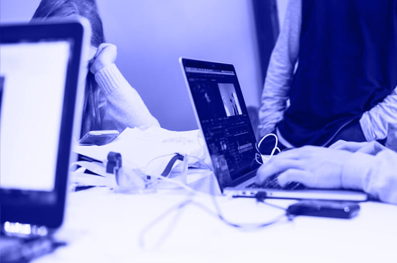 Blue Image of People Working on Laptops at a Desk