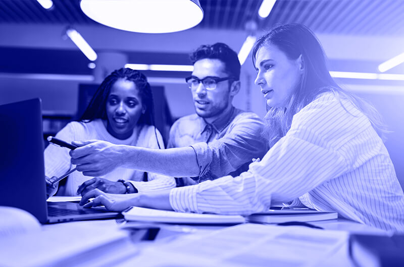 Blue Image of Three People Looking at a Laptop at a Table